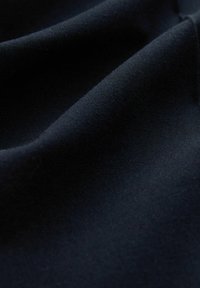 Tissu bleu foncé à texture lisse, présentant de doux plis et plis, adapté aux vêtements ou à la tapisserie.