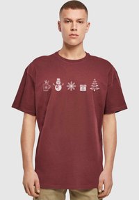 Bordeaux farvet bomulds T-shirt med hvide, festlige grafikker: en kop, en snemænd, snefnug, gaveæske og et juletræ på forsiden.