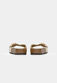 Paire de sandales beige à bouts ouverts avec semelles en liège et brides ajustables, vues de dos sur un fond clair uni.