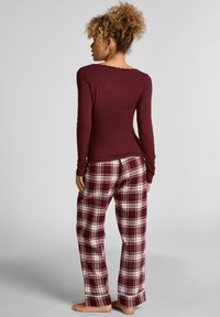Bordeaux langemouwtop met kantafwerking, gecombineerd met geruite pyjamabroek in rood, wit en donkergrijs. Zachte katoenmix stof, relaxte fit.