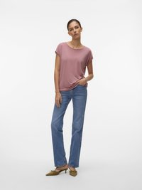 Korte mouwen, stofroze T-shirt gecombineerd met lichtblauwe straight-leg jeans en groene pumps met puntige neuzen, benadrukt door een casual pasvorm.