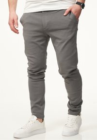 Gray sweatpants with a slim fit, made from soft fabric. Features side pockets and a smooth texture, paired with white sneakers.