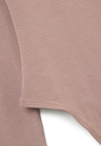 Tessuto nocciola con una superficie liscia, caratterizzato da un orlo curvo e cuciture semplici. Il materiale appare morbido ed è leggero.