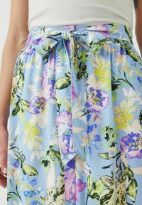 Ljusblå blommig kjol med livliga lila, gröna och rosa blommor. Knytning i midjan med en rosett; inkluderar en knappdetalj.