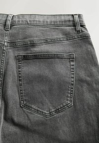 Grå denimjeans med en baglomme med synlig stikning. Stoffet har en blød struktur og subtile nuanceforskelle.