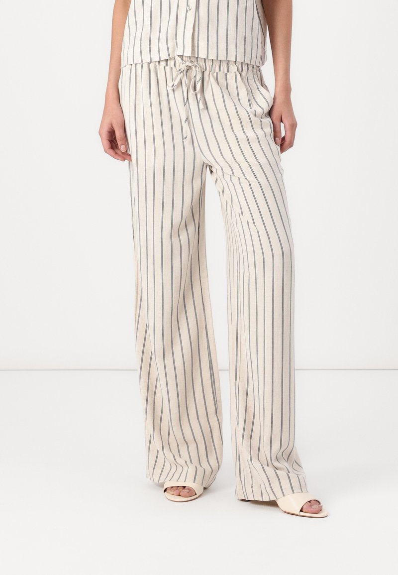 Pantalons évasés en mélange de lin, couleur crème avec des rayures verticales bleu marine. Comprend une taille élastique avec un cordon de serrage pour un ajustement réglable.
