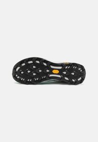 Svart gummisåle med et multidireksjonelt sålemønster, med en gul Vibram-logo og hvite detaljeringer på mellomsålen.
