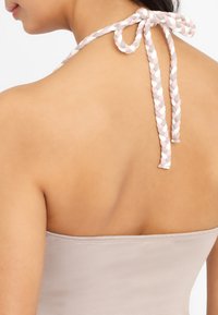 Trägerloses Top in Nude mit glatter Textur. Geflochtener Bindegürtel auf der Rückseite mit rosa, weißen und grauen Akzenten.