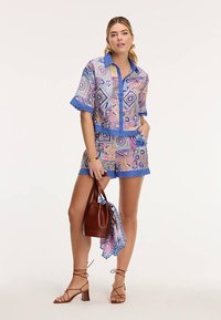 Színes mintás rövid ujjú ing és hozzáillő rövidnadrág rózsaszín, kék és krémszínben. Tartozik hozzá egy barna kézitáska és egy mintás sál.