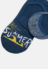 Calcetines azul marino con un diseño de ola amarilla y un estallido de sol, con el texto "VERANO" en blanco. Textura suave con aberturas elásticas.