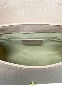 Ljust rosa texturerad läderhandväska med en slät foder, har en dragkedjeficka och detaljer i guld.