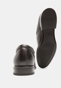 Zapatos de vestir de cuero negro con un acabado suave, con punta redondeada, costuras decorativas y suela de goma texturizada.