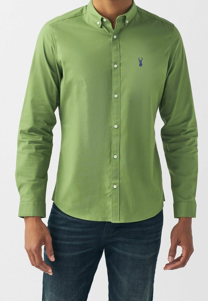 Camicia verde a maniche lunghe con colletto button-down, in tessuto verde più chiaro, e un piccolo logo blu sul petto sinistro. Vestibilità standard.