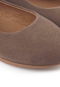 Bailarinas de ante marrón con punta redondeada, textura suave y suela de color marrón claro. La parte superior tiene un acabado liso y un diseño de corte bajo.
