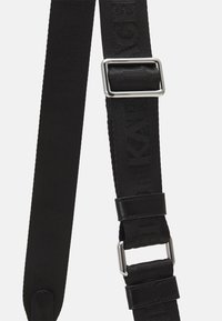 Czarny regulowany pasek wykonany z tkaniny o splocie, z metalowym zapięciem i skórzanymi akcentami. Pasek ma teksturowaną powierzchnię.