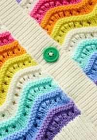 Cardigan a maglia con una base color crema e motivi a onde colorati in rosa, arancione, giallo, verde, blu e viola. Dettaglio dei bottoni verde.