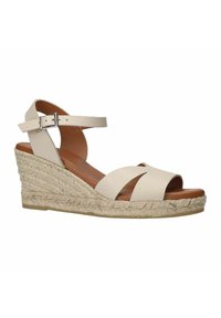 Wedge-Sandale aus cremefarbenem, strukturiertem Leder mit breiten Kreuzriemen. Sie verfügt über eine geflochtene Jutesohle und einen verstellbaren Knöchelriemen mit einer Metallschnalle.