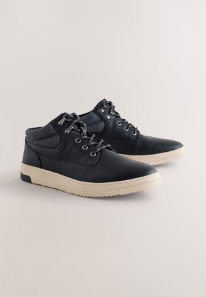 Zwarte leren schoenen met een grijze textielkraag, versterkte veterogen, ronde veters en een beige rubberen zool. Voorzien van stevige stiksels en een textuurcontrast.