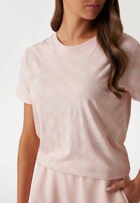 Light pink short-sleeved t-shirt made of soft fabric, featuring a subtle all-over pattern and sparkling accents in a round shape.