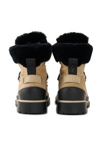 Voděodolné béžové semišové boty s černým umělým kožešinovým lemováním, plochou černou podešví a krémovými akcenty, s ozdobným poutkem na zadní straně a kovovými sponami.