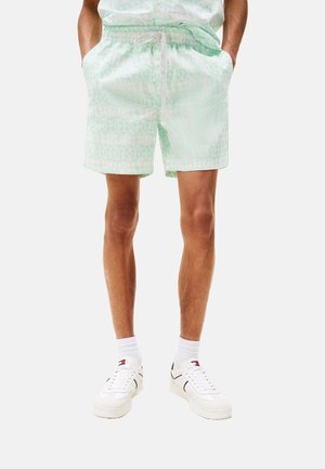 Bañador de patrón verde claro con cintura elástica y cordón. Combinado con zapatillas blancas y calcetines blancos.