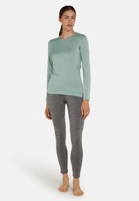 Top lungo azzurro chiaro con maniche lunghe realizzato in tessuto liscio, abbinato a leggings grigi aderenti con una morbida texture mélange.