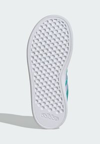 Bílá gumová podrážka boty s texturovaným vzorem včelí plástve. Obsahuje logo "adidas" blízko paty. Oblouk obrysuje hranu.