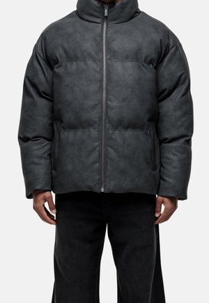 Veste matelassée gris foncé en matériau texturé. Elle présente un col montant, une fermeture éclair frontale et des poches latérales. Design minimaliste sans motifs.