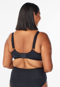 Melnas bikini augšdaļas ar regulējamiem siksniņām un aizmugurē ar āķa aizdari. Vienkāršs dizains, gluda tekstūra un bezšuvju konstrukcija.