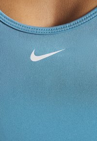 Top sportivo blu in tessuto liscio e strutturato con scollatura a girocollo, caratterizzato da un logo Nike bianco sul davanti.