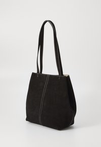 Geanta tote din suede negru, cu două mânere lungi, cusături albe contrastante și un design spațios, lejer. Textură netedă fără hardware vizibil.