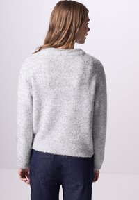 Hellgrauer, flauschiger Pullover mit rundem Halsausschnitt und langen Ärmeln. Hat einen leicht verkürzten Saum und einen weichen, strukturierten Stoff.