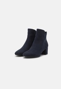 Navyblaue Wildleder-Stiefeletten mit einer spitzen Spitze und einem klobigen Absatz, die eine glatte Textur und ein minimalistisches Design aufweisen.