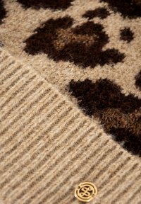 Maglione beige con un motivo animalier marrone e beige, orlato a costine e con un accento in oro del logo. Materiale in lana morbida e testurizzata.