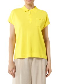 Gelbes Poloshirt mit kurzen Ärmeln, Kragen, drei Knöpfen und einer Brusttasche. Glatte Textur und entspannter Schnitt.