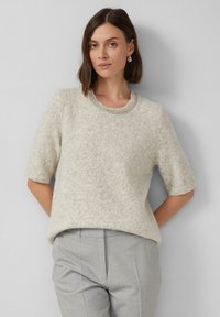 Jasnoszara krótko-sleeve sweter z miękkiego, teksturowanego materiału z perłowym dekoltem, w zestawieniu z jasnoszarymi, teksturowanymi spodniami.