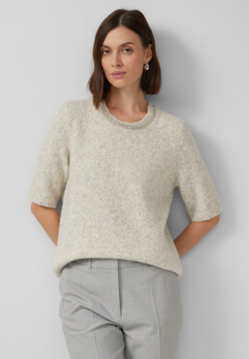 Jasnoszara krótko-sleeve sweter z miękkiego, teksturowanego materiału z perłowym dekoltem, w zestawieniu z jasnoszarymi, teksturowanymi spodniami.