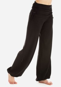 Black wide-legged pants with a ruched waist and adjustable drawstring, made of soft fabric, featuring side pockets and a relaxed fit.