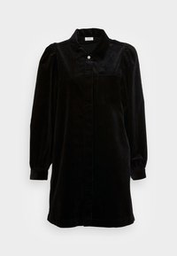 Abito camicia in velluto a coste nero con colletto, chiusura frontale a bottoni, maniche lunghe e una tasca sul petto. Texture morbida e vestibilità sartoriale.