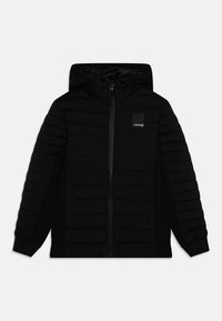 Veste noire à capuche avec un design matelassé sur le devant, tissu doux, fermeture éclair et poches latérales. Logo simple sur la poitrine.