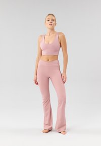 Set fitness rosa chiaro a coste con crop top senza cuciture e spalline larghe, abbinato a pantaloni a zampa a vita alta con un design sottile in vita.