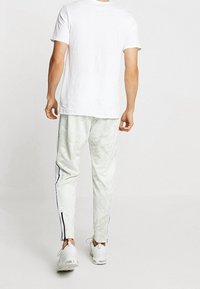 Vit bomull t-shirt med korta ärmar, i kombination med ljusgrå mönstrade joggers med sidostripes och en smal passform.