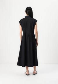 Vestido preto de mangas curtas com gola, cintura ajustada e saia fluida. Tecido texturizado e design até ao tornozelo.