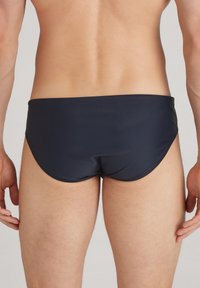 Herren Badebriefe in Marineblau, aus einem glatten, dehnbaren Stoff gefertigt. Mit einem tief sitzenden Schnitt und minimalen Nähten für eine schlanke Form.