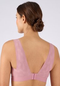 Soutien-gorge sans fil rose avec un motif de fougère texturé, larges bretelles et un design à dos en V profond. Équipé d'une fermeture à crochets et œillets à l'arrière.