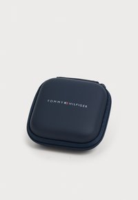 Carcasă dură de culoare albastru marin cu închidere prin fermoar, având un logo pe partea din față. Textură netedă, colțuri rotunjite și un design robust.
