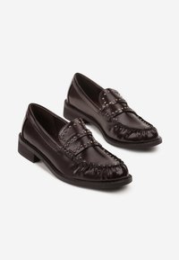 Une paire de mocassins en cuir marron foncé avec des détails cloutés et de petits talons en bois sur un fond blanc.