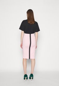 Black short-sleeve shirt, fitted pink pencil skirt with a back zipper, and green fuzzy high-heeled shoes. Neutral background.