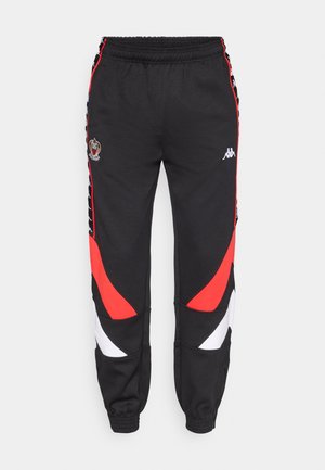 Schwarze Sporthose mit roten und weißen Akzenten, elastischem Bund, Kappa-Logo und seitlichen Einsätzen mit einem einzigartigen Wellenmuster.