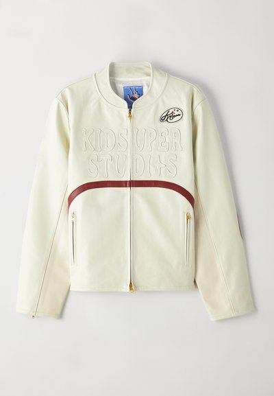 Cream-colored leather jacket with a bomber style, ribbed collar, embroidered "KIDS SUPER STUDIOS," burgundy accents, and zippered pockets.